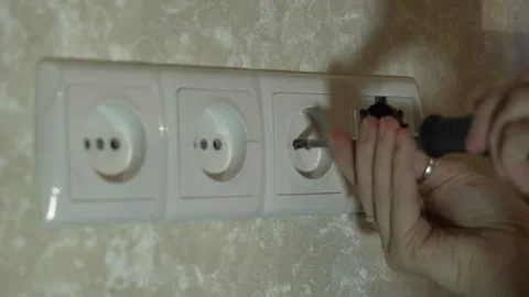 Hands of a girl using a screwdriver when installing a electrical outlet Video stock 258766549