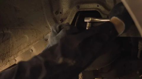 Hands in gloves and work clothes are repairing a spare part of a car in a garage Video stock 129824535