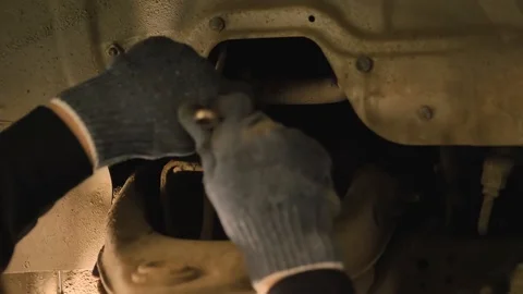 Hands in gloves and work clothes are repairing a spare part of a car in a garage Video stock 129824715