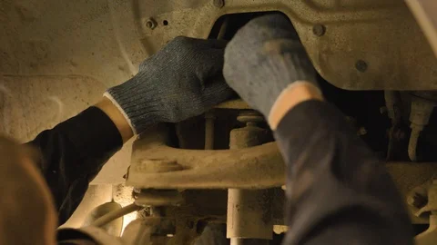 Hands in gloves and work clothes are repairing a spare part of a car in a garage Video stock 129824831