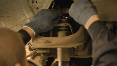 Hands in gloves and work clothes are repairing a spare part of a car in a garage Video stock 129824974