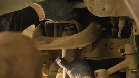 Hands in gloves and work clothes are repairing a spare part of a car in a garage Video stock 129825100