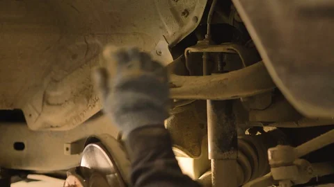 Hands in gloves and work clothes are repairing a spare part of a car in a garage Video stock 129825228
