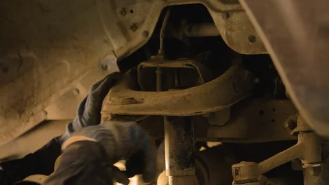 Hands in gloves and work clothes are repairing a spare part of a car in a garage Video stock 129825478