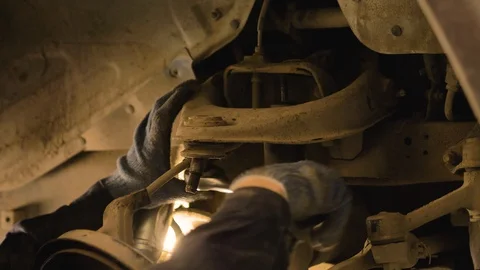 Hands in gloves and work clothes are repairing a spare part of a car in a garage Video stock 129825710