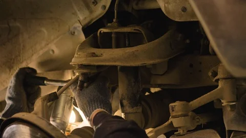 Hands in gloves and work clothes are repairing a spare part of a car in a garage Video stock 129825959