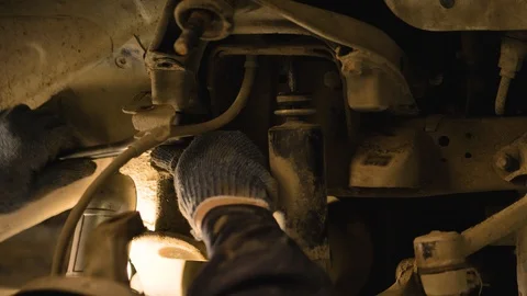 Hands in gloves and work clothes are repairing a spare part of a car in a garage Video stock 129826200