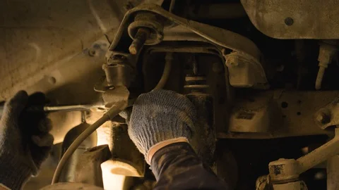 Hands in gloves and work clothes are repairing a spare part of a car in a garage Video stock 129826447