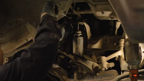 Hands in gloves and work clothes are repairing a spare part of a car in a garage Video stock 129834810