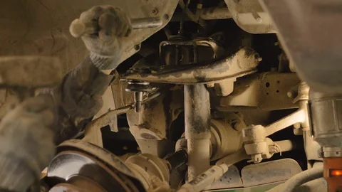 Hands in gloves and work clothes are repairing a spare part of a car in a garage Video stock 129835650