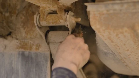 Hands in gloves and work clothes are repairing a spare part of a car in a garage Stock Footage 129839702