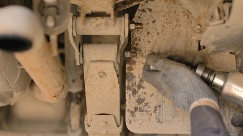 Hands in gloves and work clothes are repairing a spare part of a car in a garage Stock Footage 129839798