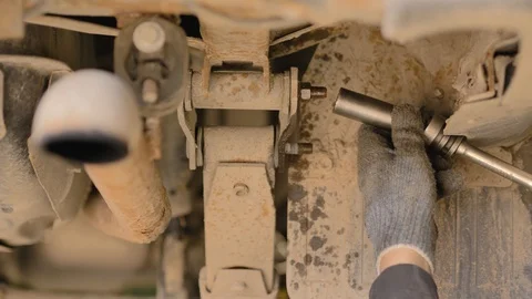 Hands in gloves and work clothes are repairing a spare part of a car in a garage Stock Footage 129839874