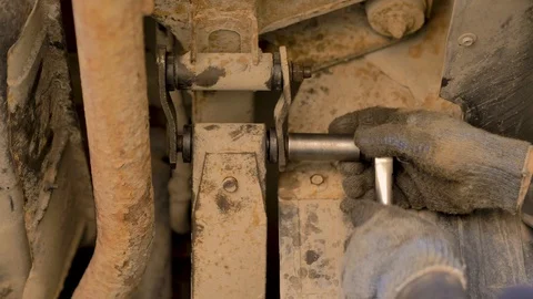 Hands in gloves and work clothes are repairing a spare part of a car in a garage Stock Footage 129841368