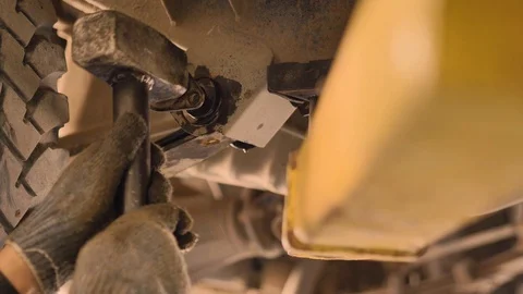 Hands in gloves and work clothes are repairing a spare part of a car in a garage Stock Footage 129843466