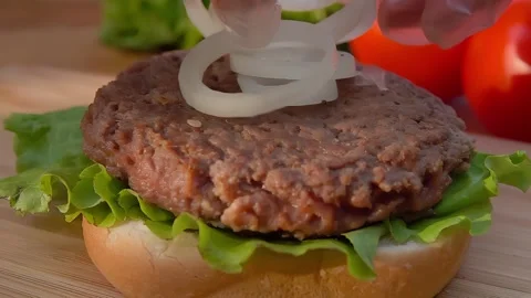 Hands in gloves are laying fresh onion rings on the burger Stock Footage 287447723