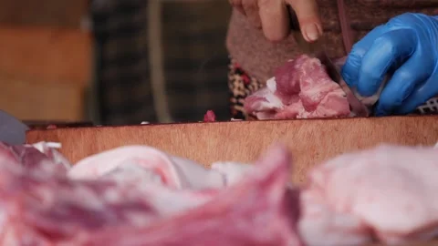 Hands in gloves cut raw meat on a market counter with a knife. Meat slicing. 스톡 동영상 341408708