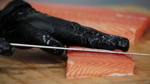 Hands with gloves cut red salmon with a knife on a wooden board Stock Footage 127203261