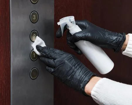 Hands with gloves disinfecting elevator buttons Stock-Fotos