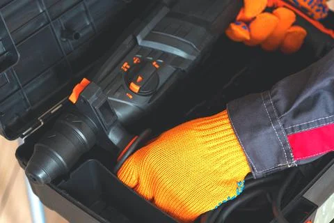 Hands in gloves, hammer drill, perforator. tool box Stock Photos