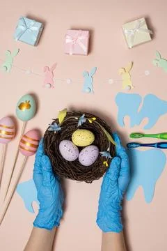 Hands in gloves holding an Easter nest with colored eggs. Greeting Medical De Stock Photos