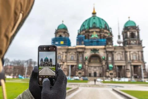 Hands with gloves holding a smartphone and taking a picture of the Berlin Cat Stock Photos