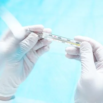 Hands in gloves holding termometr with elevated body temperature. Stock Photos