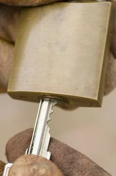 Hands in gloves with key in padlock Foto stock