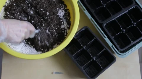Hands in gloves mix the soil with useful additives and prepare for planting. Stock Footage 266898798