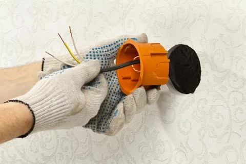 Hands in gloves mount the socket box on the wall Stock Photos