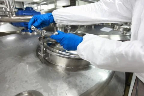 Hands in gloves opening industrial process tank Stock Photos