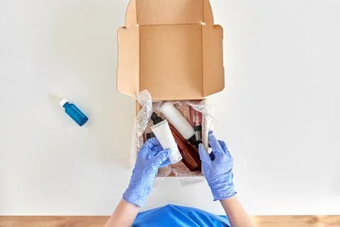 Hands in gloves packing parcel box with cosmetics Stockfoto's