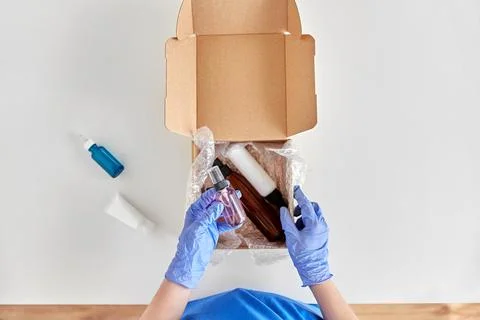 Hands in gloves packing parcel box with cosmetics 库存照片