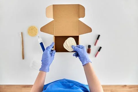 Hands in gloves packing parcel box with cosmetics 스톡 사진
