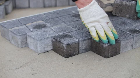 Hands in gloves placing paving blocks on sand base Stock Footage 315562481