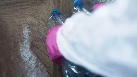 Hands in gloves put plastic bottles into bag to protect the enviroment from the Video stock 119985000