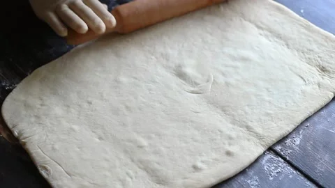 Hands in gloves roll out the dough on a wooden background. Cooking. Bakery produ Vídeo Stock 147547323