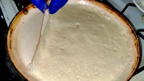 Hands in gloves separate the baked pancake from the pan.  Cooking pancakes Stock Footage 232945778