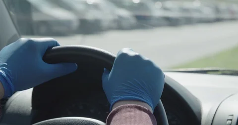 Hands in gloves on steering wheel driving a car covid 19 pandemic crisis Stock Footage
