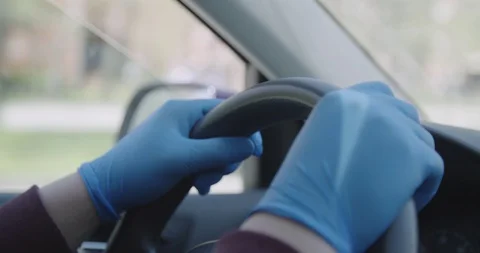 Hands in gloves on steering wheel driving a car covid 19 pandemic crisis Stock Footage 127854309