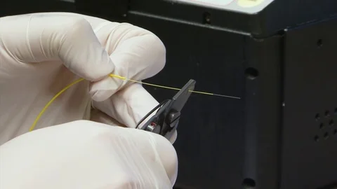 Hands with gloves stripping a fiber optic cable with a wire stripper Vidéo 121781168