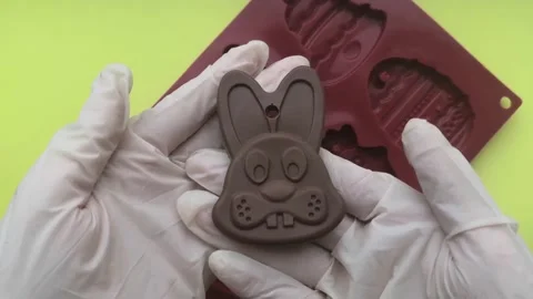 Hands in gloves taking out chocolate bunny from silicone mold. Happy easter for Stock Footage 150664237