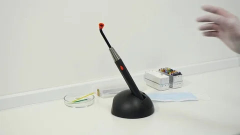 Hands in the gloves taking from the power base a Polymerization dental lamp. Video stock 83621829