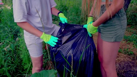 Hands in gloves tying top of full garbage bag close up Stock Footage 340464636