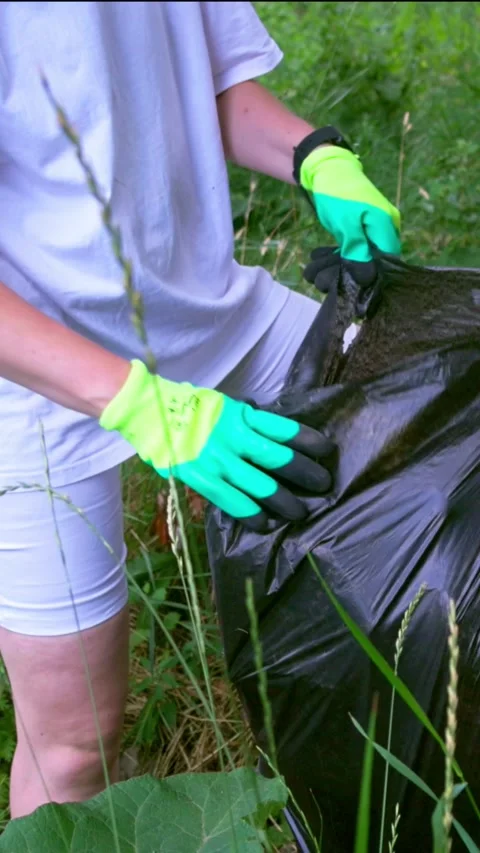 Hands in gloves tying top of full garbage bag close up Stock Footage 340577642