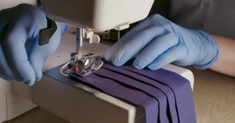 Hands in gloves using sewing machine to sewing medical face mask. Stock Footage 141073219