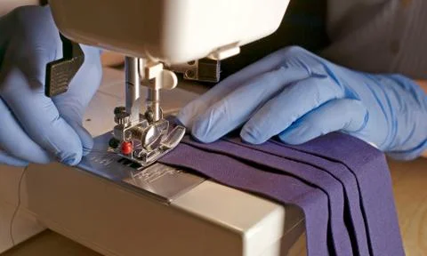 Hands in gloves using sewing machine to sewing face mask Stock Photos