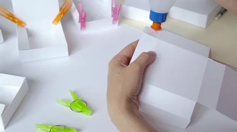 Hands gluing paper box template and clamping details with clothespins closeup Stock Footage 67689122