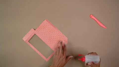 Hands Gluing Patterned Cardstock for DIY Craft Project on Tabletop with Tools Stock Footage 345617060