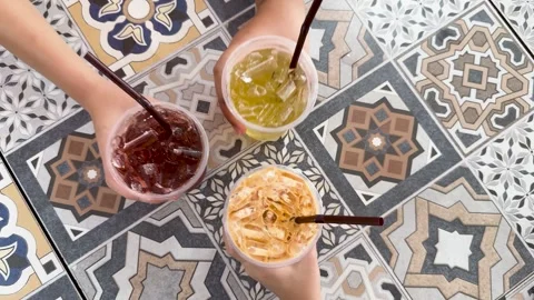 Hands Grabbing Iced Drinks from Patterned Tile Table in Phuket Stock Footage 323410942
